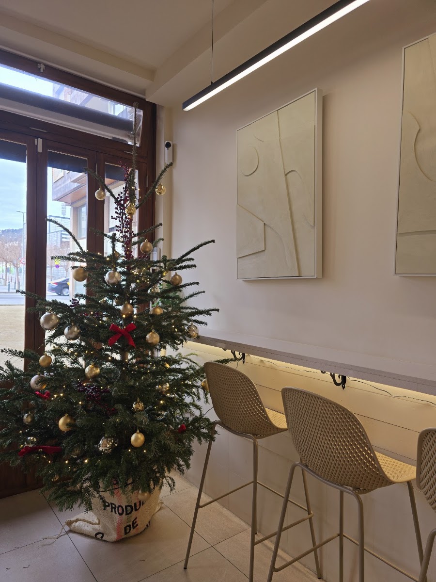 Interior del restaurante con mostrador blanco, taburetes, arte minimalista y árbol de Navidad
