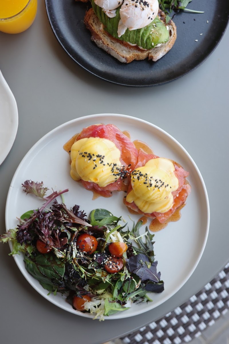 Huevos Benedict con salsa holandesa sobre salmón y muffins ingleses, ensalada con tomates cherry