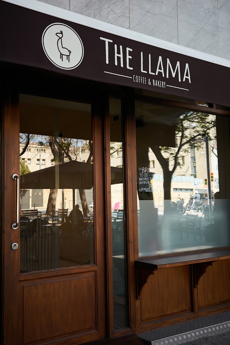 Fachada de madera oscura con entrada de vidrio y letrero The Llama Coffee & Bakery