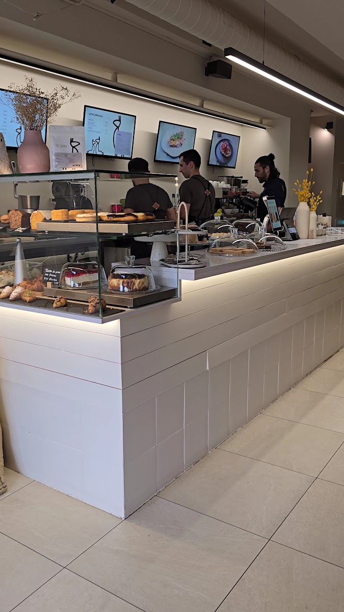 Mostrador de servicio con vitrina de pastelería y tartas, dos miembros del personal trabajando